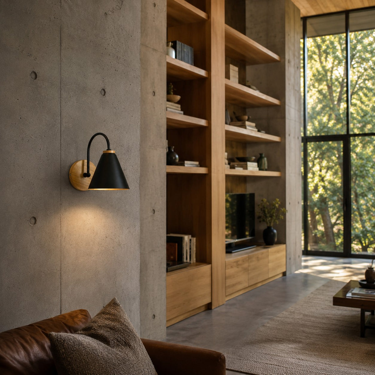 Alenquer wall sconce in black mounted on a concrete wall beside oak shelving