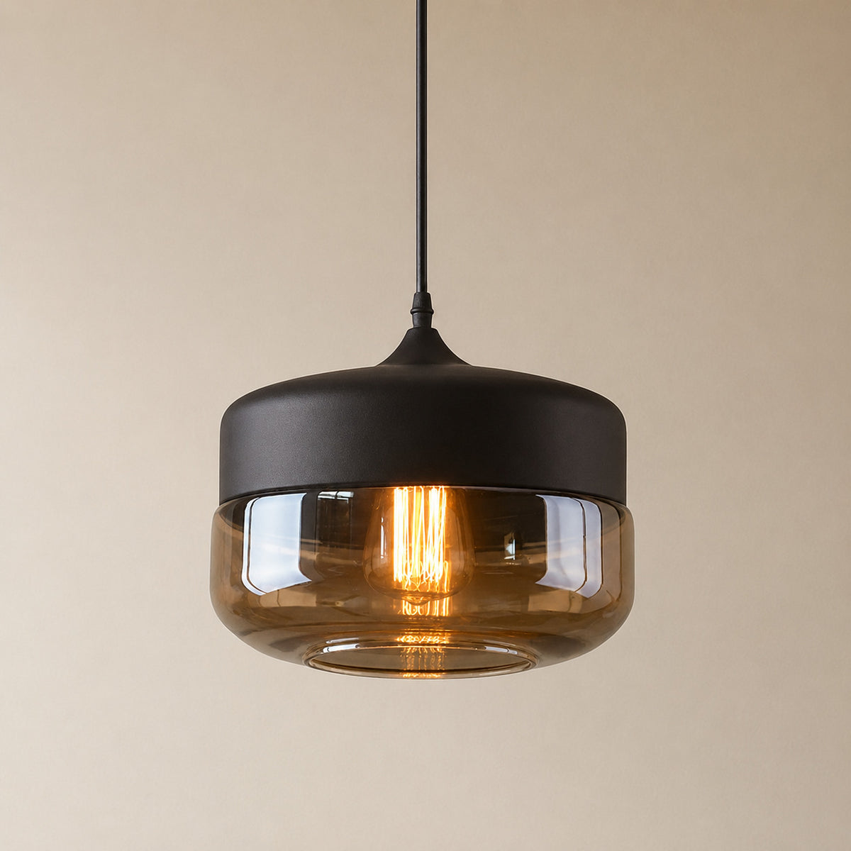 Alge glass pendant with a matte black cap and an amber glass shade, a wide shallow drum