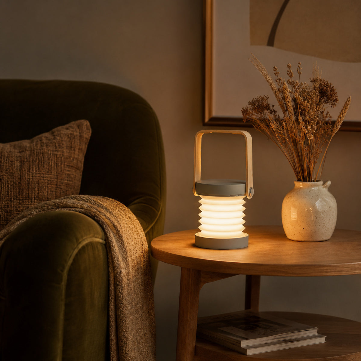 Alva lantern in grey on a side table beside a velvet armchair