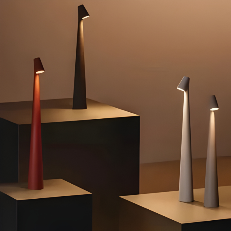 Slim cordless mood lamp on a bedside table beside a linen-bedded bed.