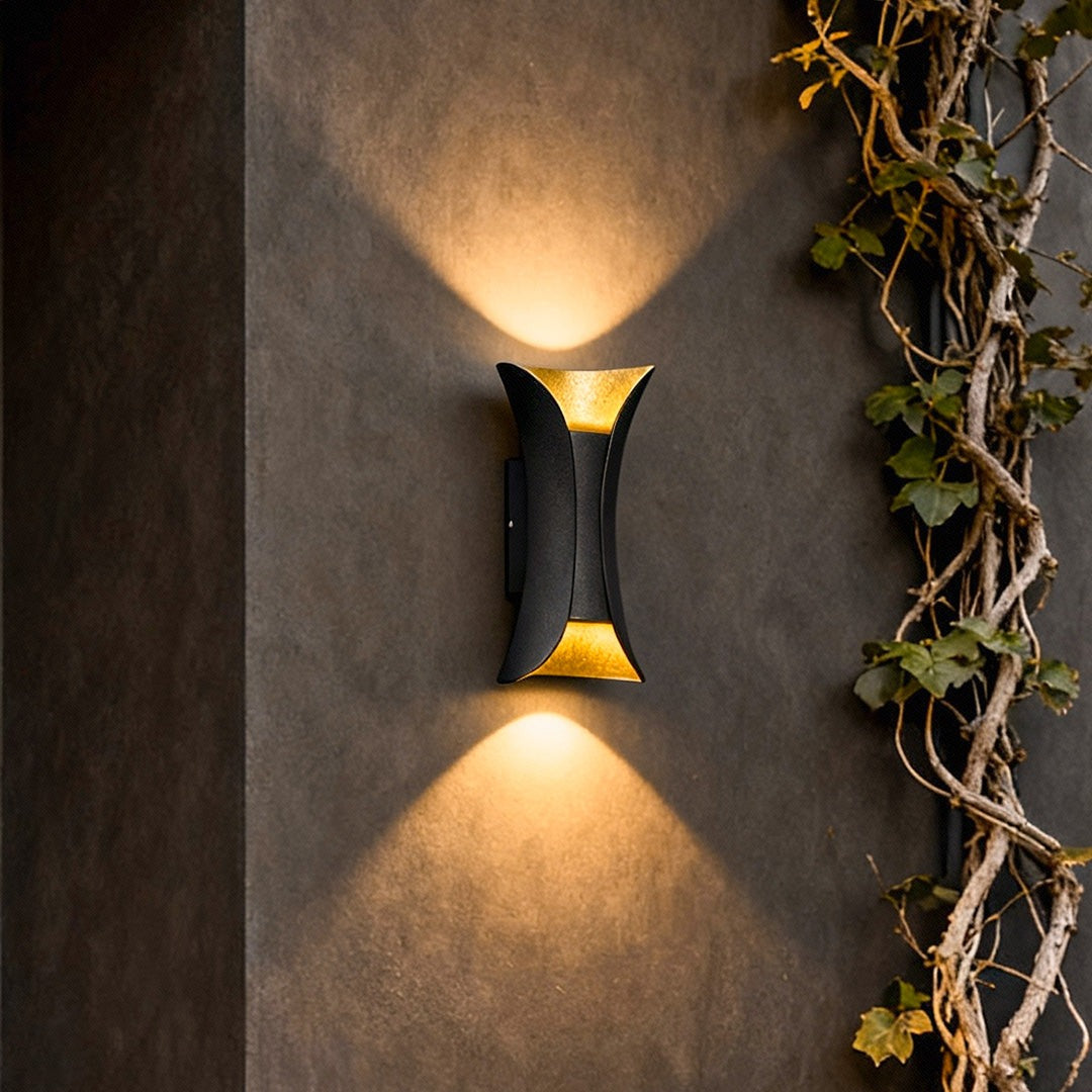 Black and gold Águeda wall light close-up detail on ivy-covered exterior wall
