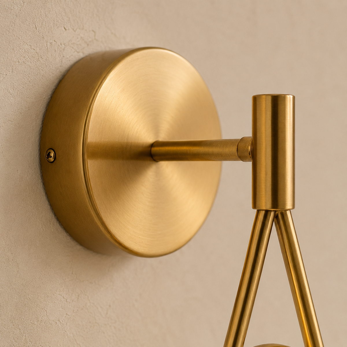 Brushed brass backplate, arm and pin joint of the Celorico sconce on cream plaster.