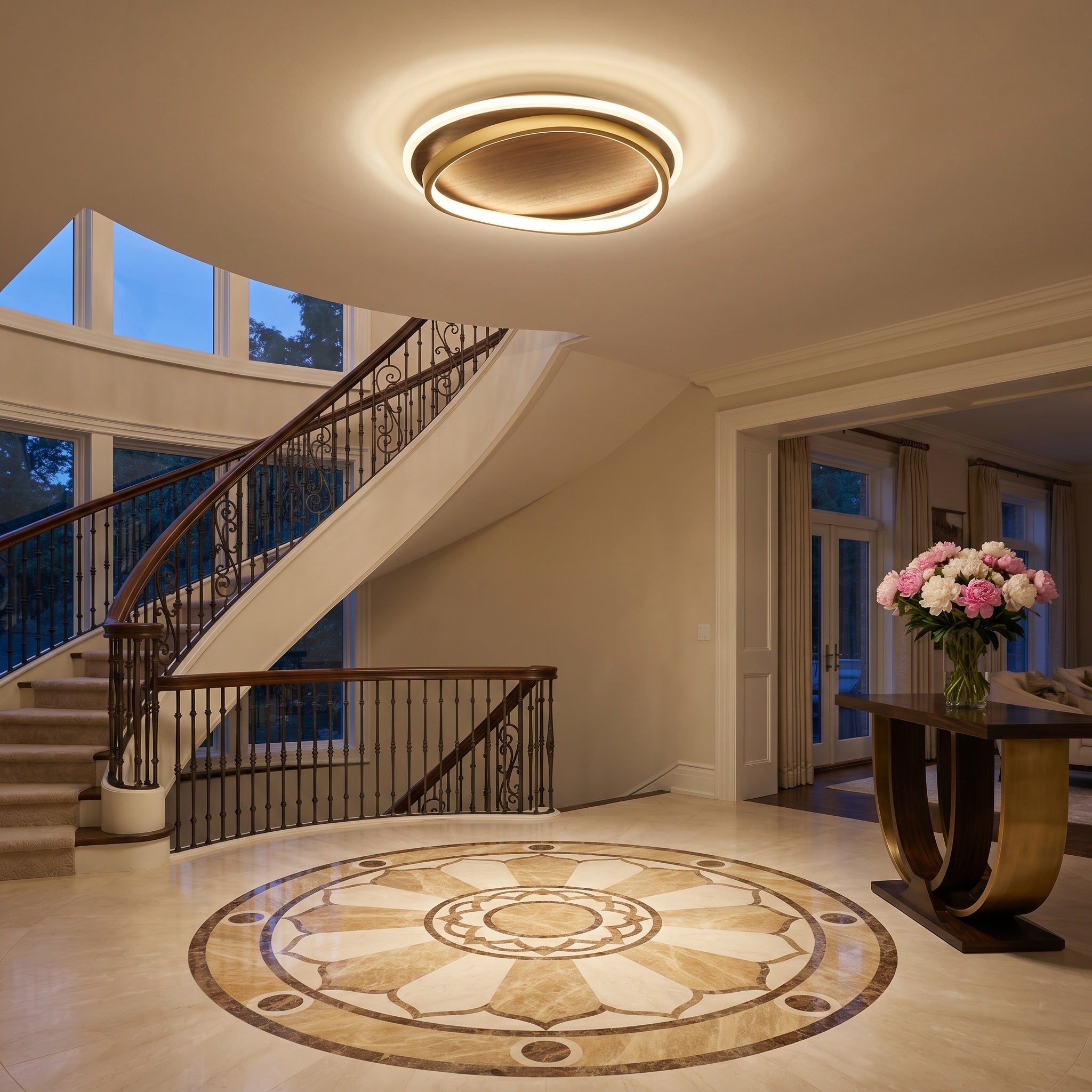 Chaves LED flush mount ceiling light, walnut finish, lighting an entry hall with curved staircase and marble floor.