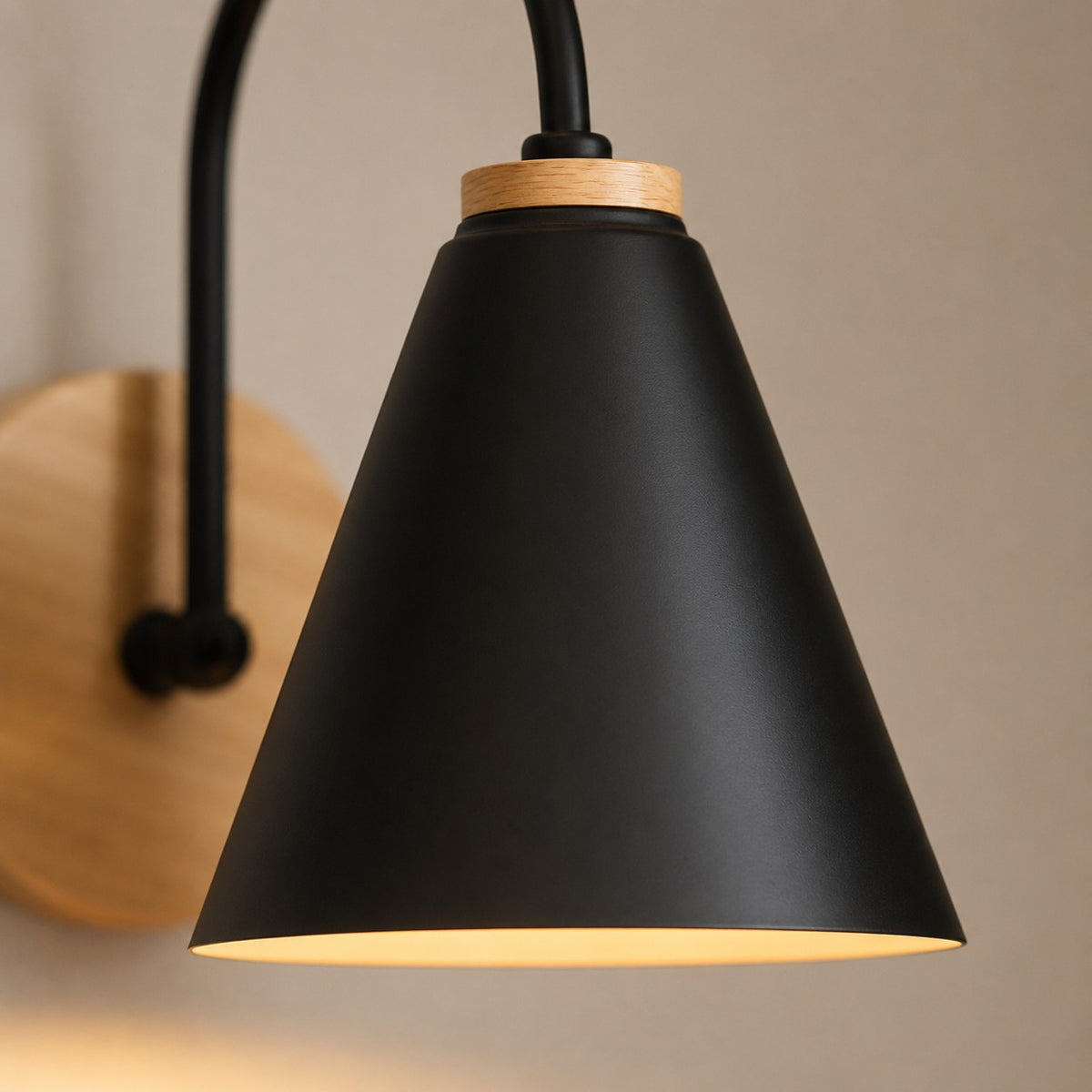 Close-up of the black cone shade with its wood collar, lamp lit