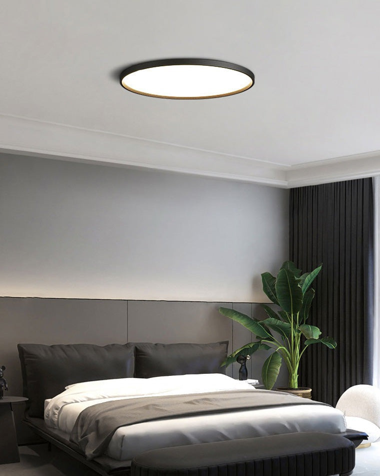 Estorãos flat round flush mount ceiling light, in a bedroom, beside a plant.