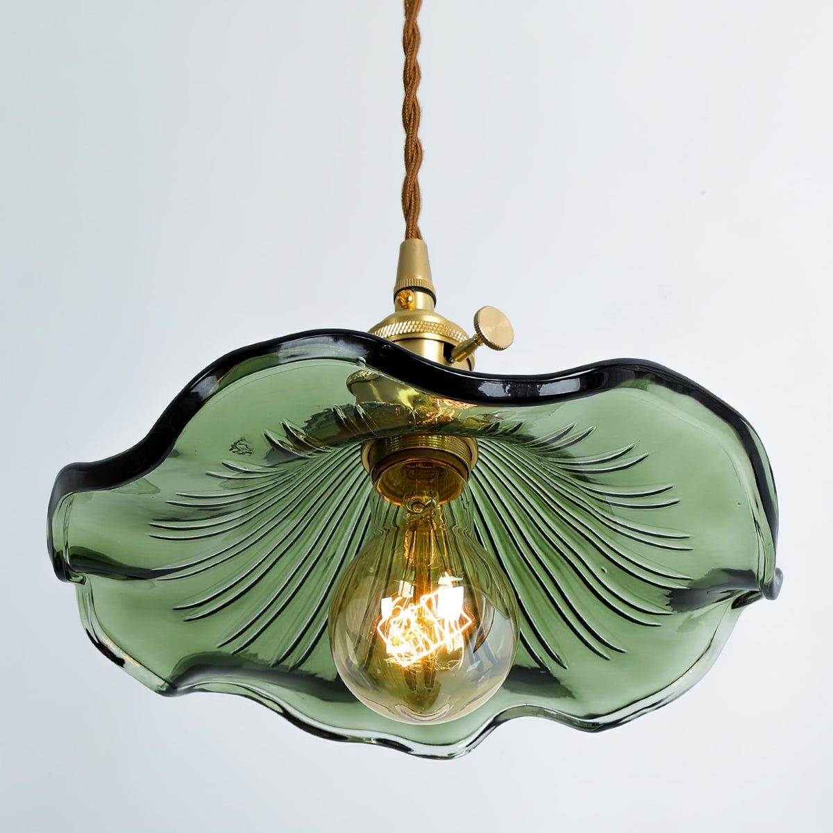 Green fluted glass shade from below with a lit Edison bulb and brass socket.
