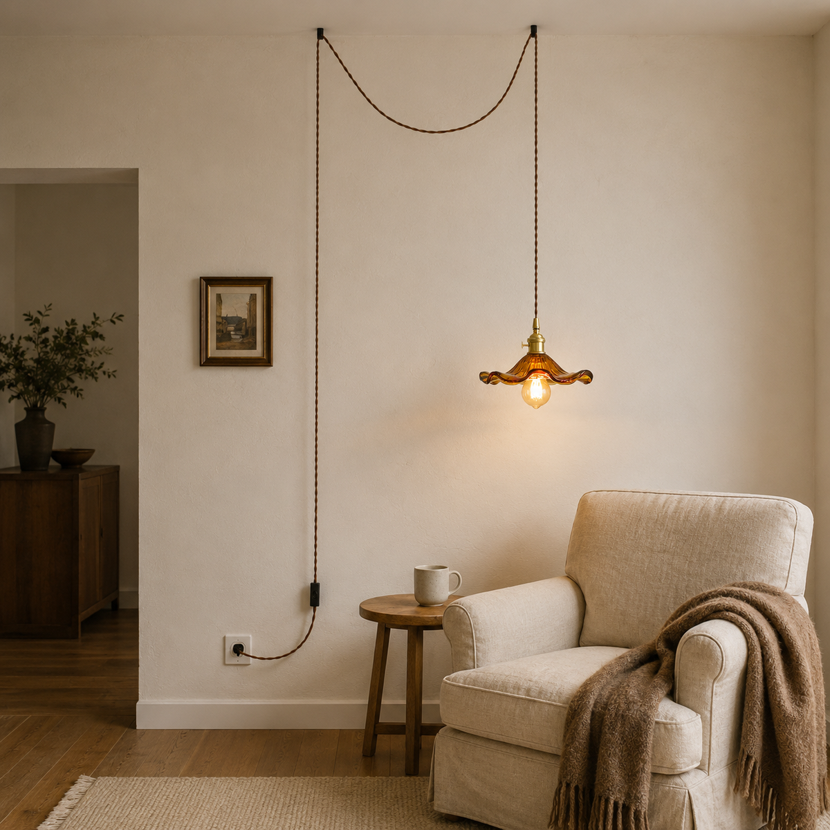 Ferragudo amber glass pendant hung from two ceiling hooks, cord running to a wall outlet by a reading chair.