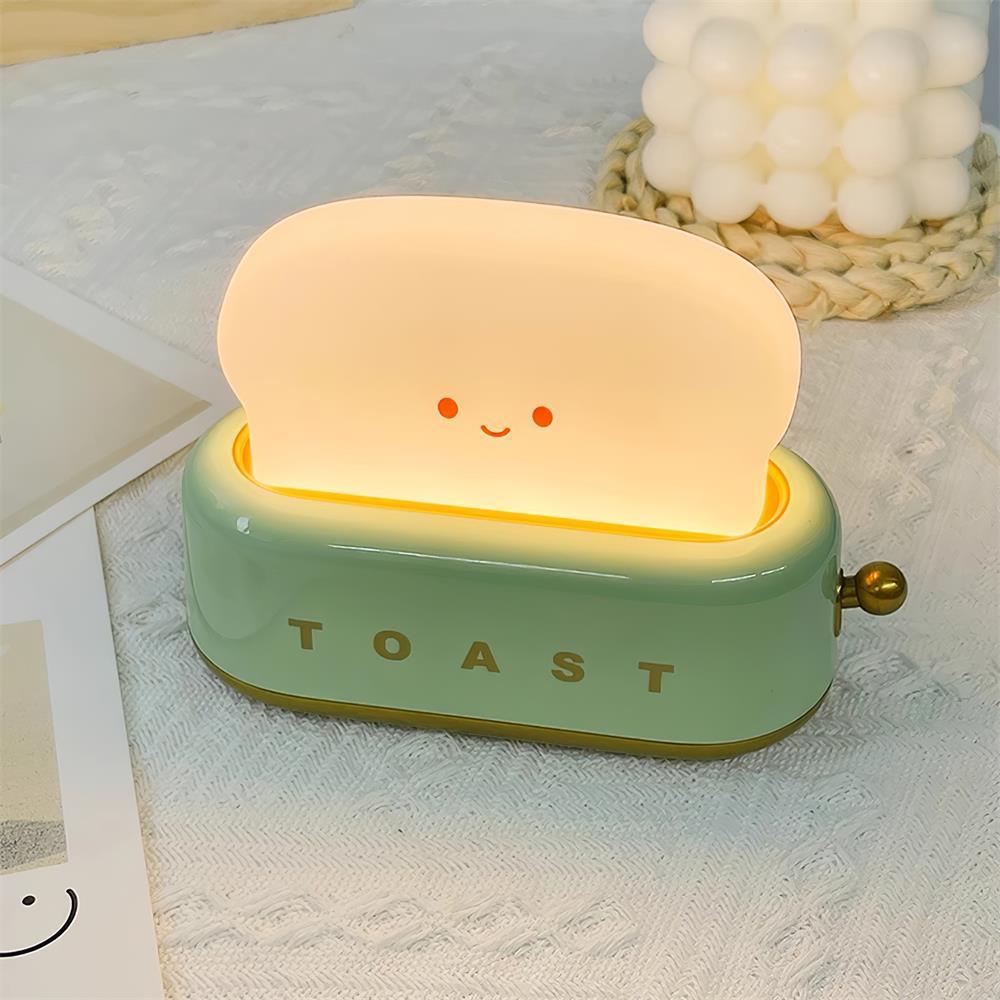 Portable toaster-shape LED night light in green with smiling toast face, product shot.
