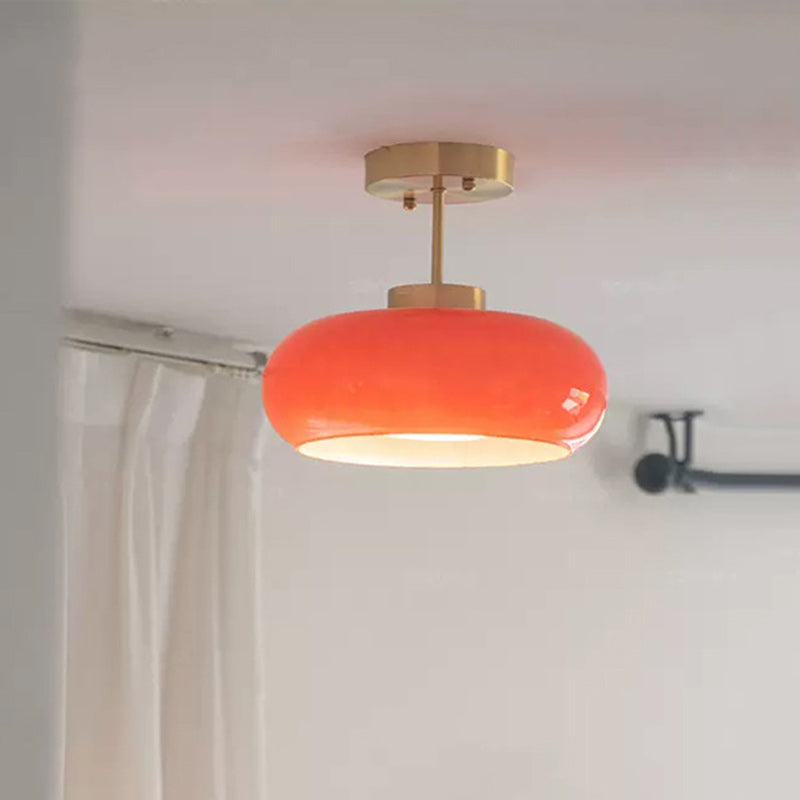 Portalegre semi-flush ceiling light with an orange-red glass dome on a brass frame, lit, ceiling mounted