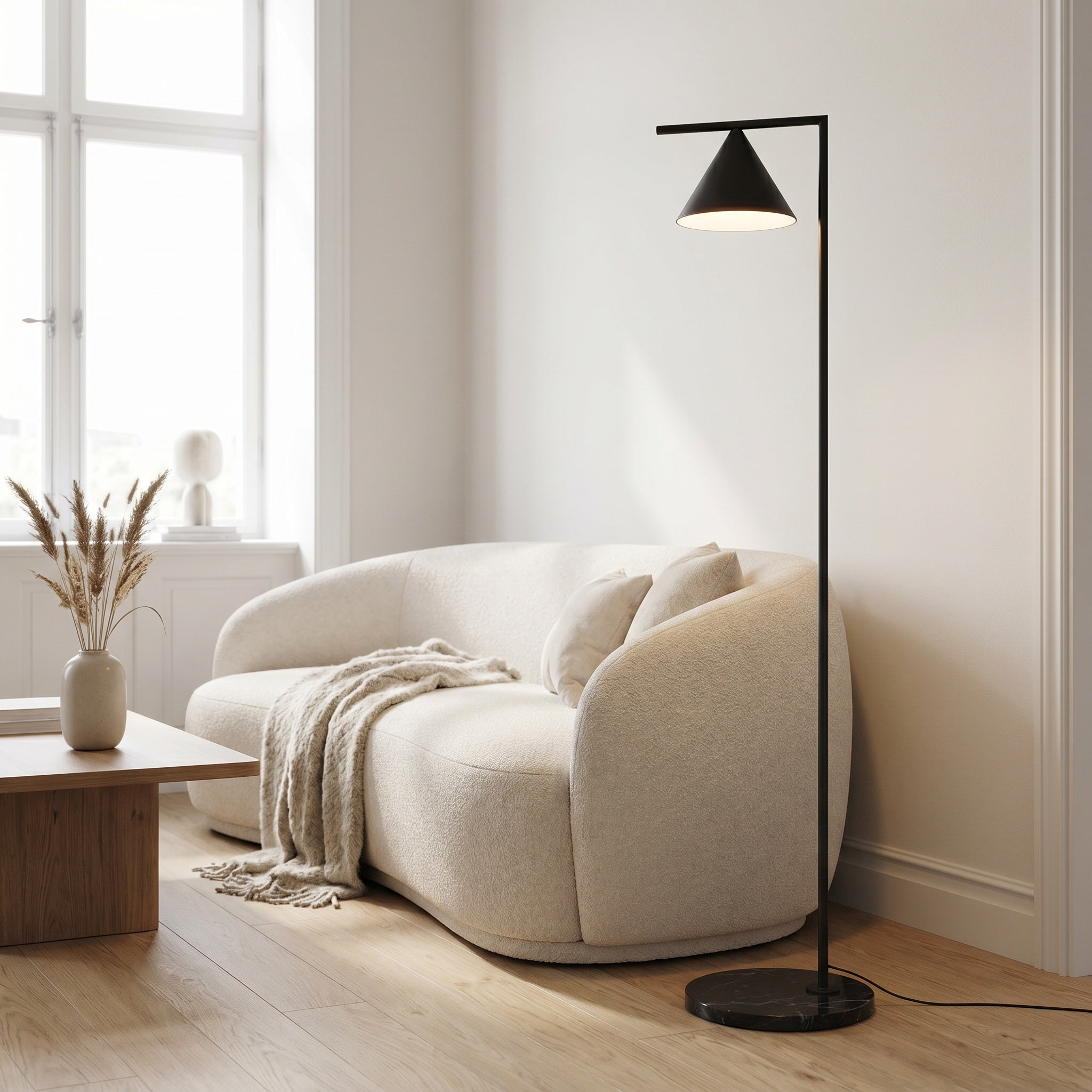Black cone floor lamp beside a boucle sofa in a bright scandinavian living room.