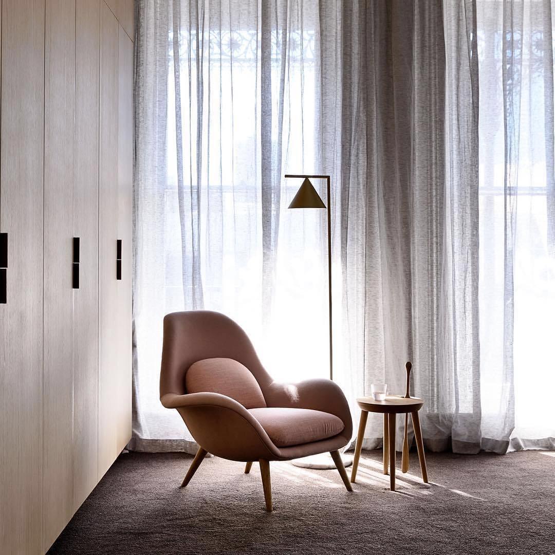 Copper cone floor lamp in a curtained room with a wing chair.