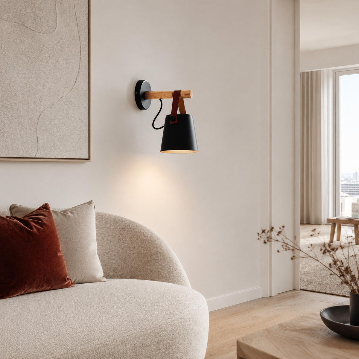 Alfusqueiro sconce in black on a white wall above a curved linen sofa