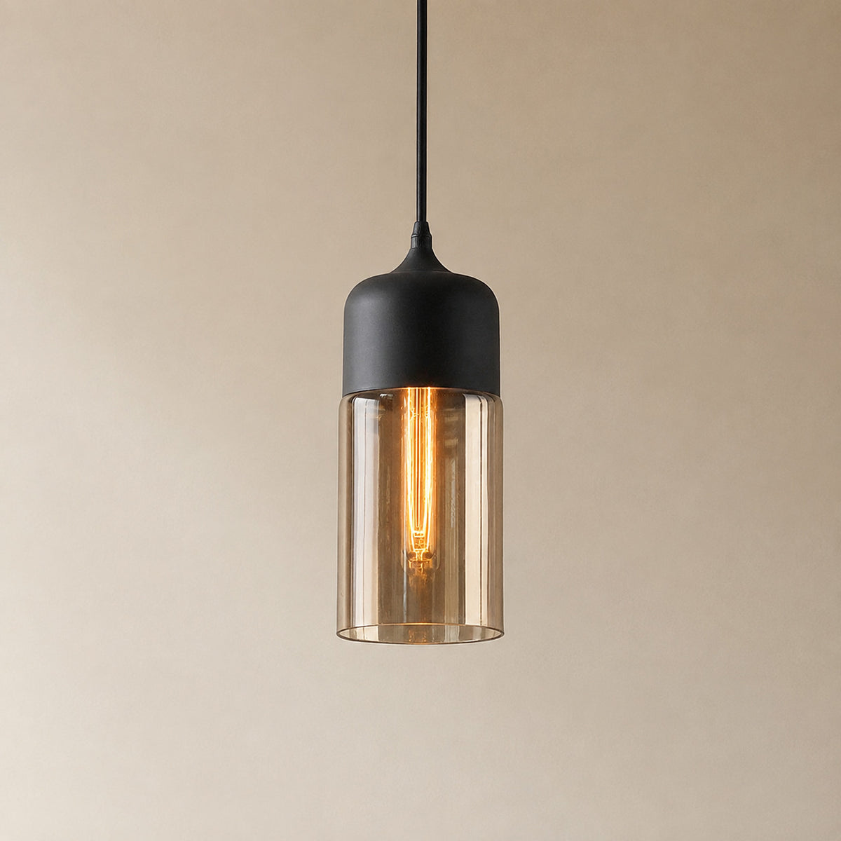 Alge glass pendant with a matte black cap and an amber glass shade, a tall narrow cylinder measuring 33 by 13 cm