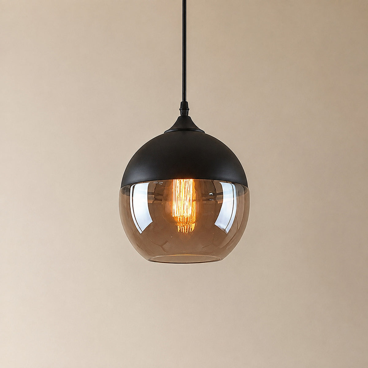 Alge glass pendant with a matte black cap and an amber glass shade, a rounded globe