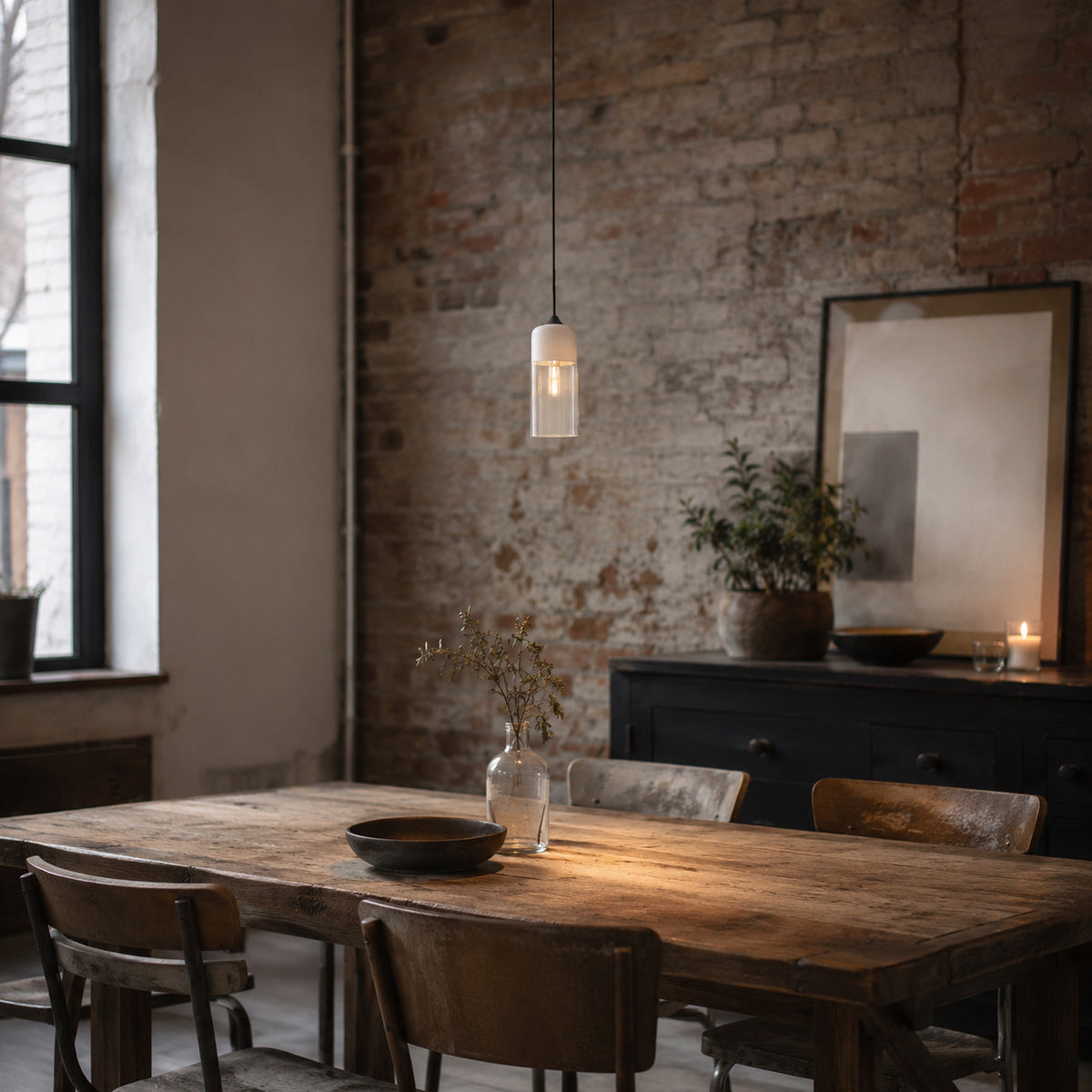 Alge pendant in white and amber, tall cylinder shape, above a reclaimed oak table in a brick loft