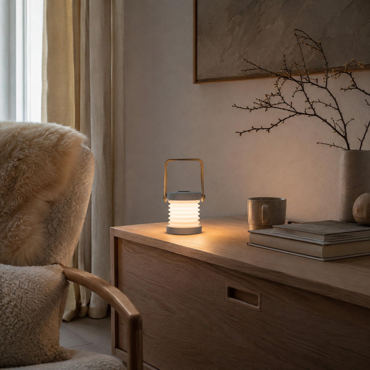 Alva lantern in grey on an oak dresser in a Scandinavian reading nook