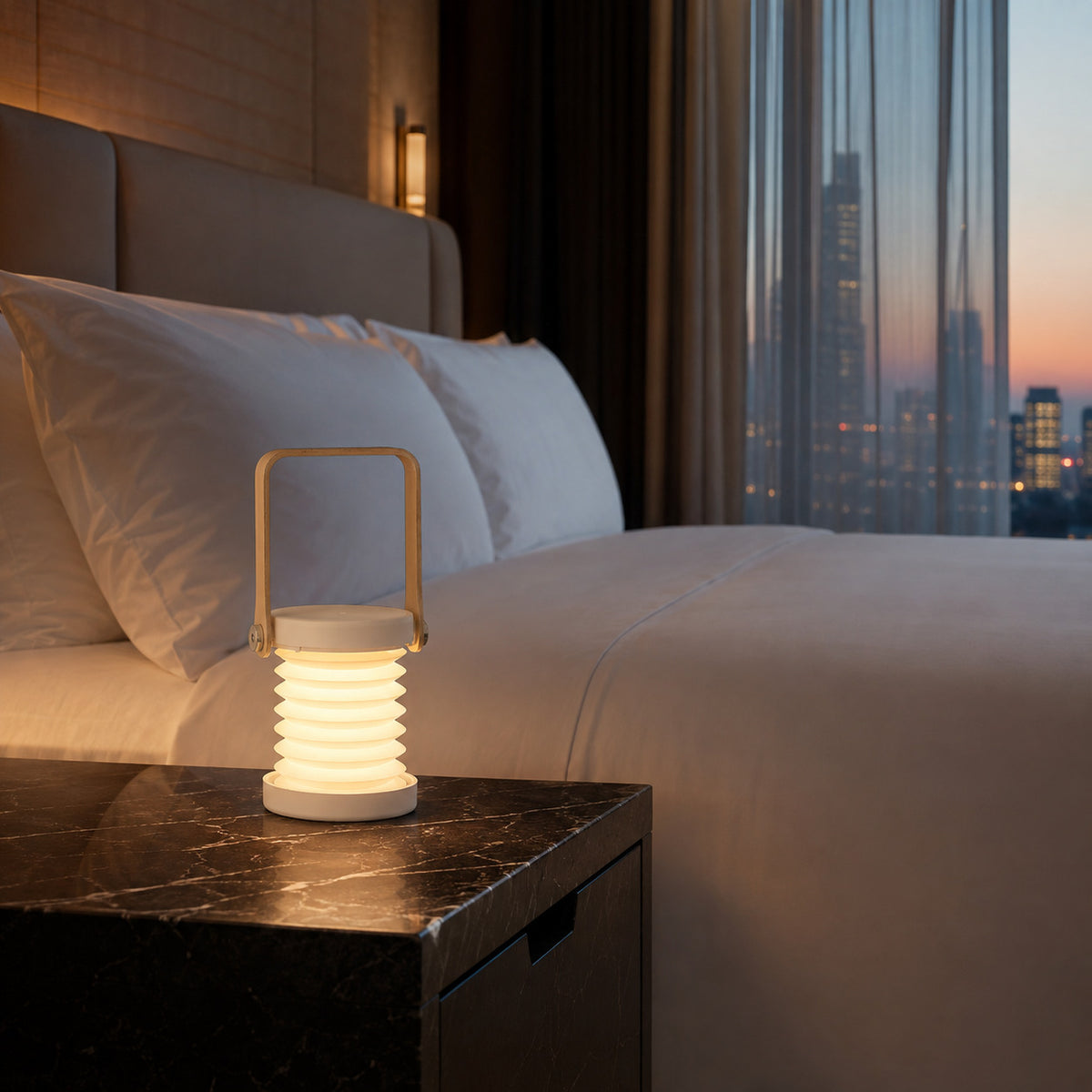 Alva lantern in white on a black marble nightstand in a city view hotel room