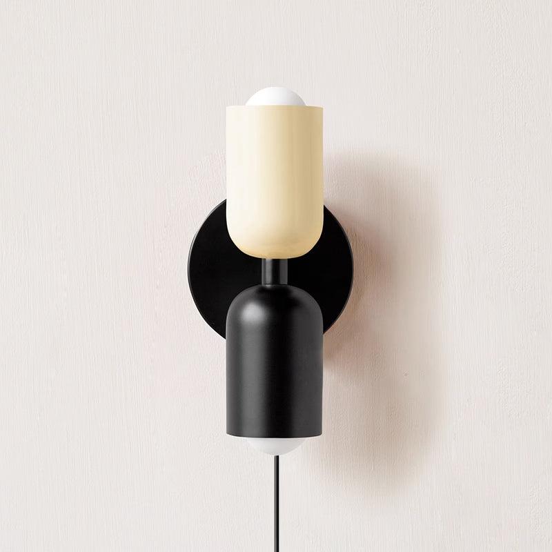 Alvor wall sconce with beige upper and black lower painted metal shades on a plaster wall