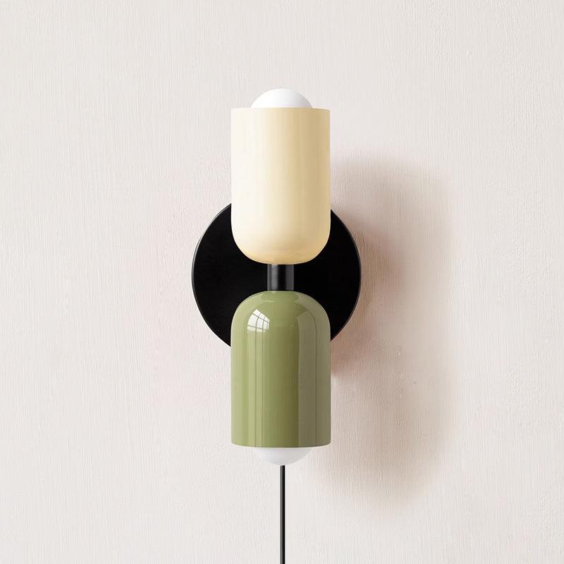 Alvor wall sconce with beige upper and green lower painted metal shades on a plaster wall