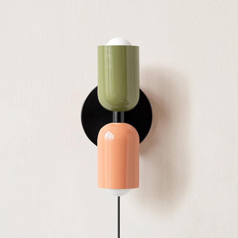 Alvor wall sconce with green upper and pink lower painted metal shades on a plaster wall