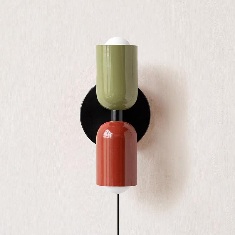 Alvor wall sconce with green upper and red lower painted metal shades on a plaster wall