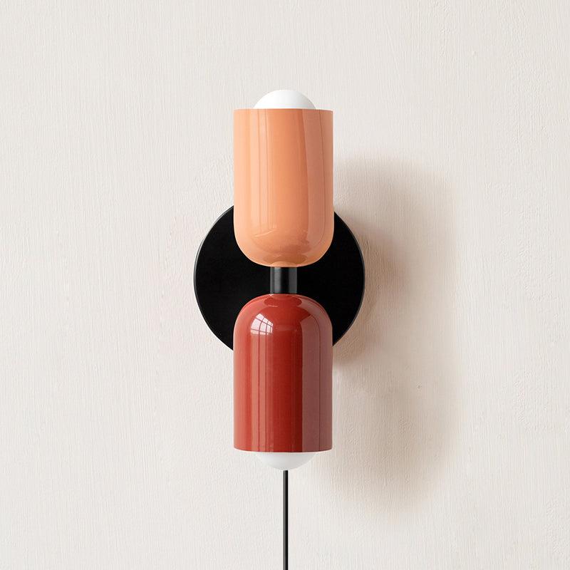 Alvor wall sconce with pink upper and red lower painted metal shades on a plaster wall