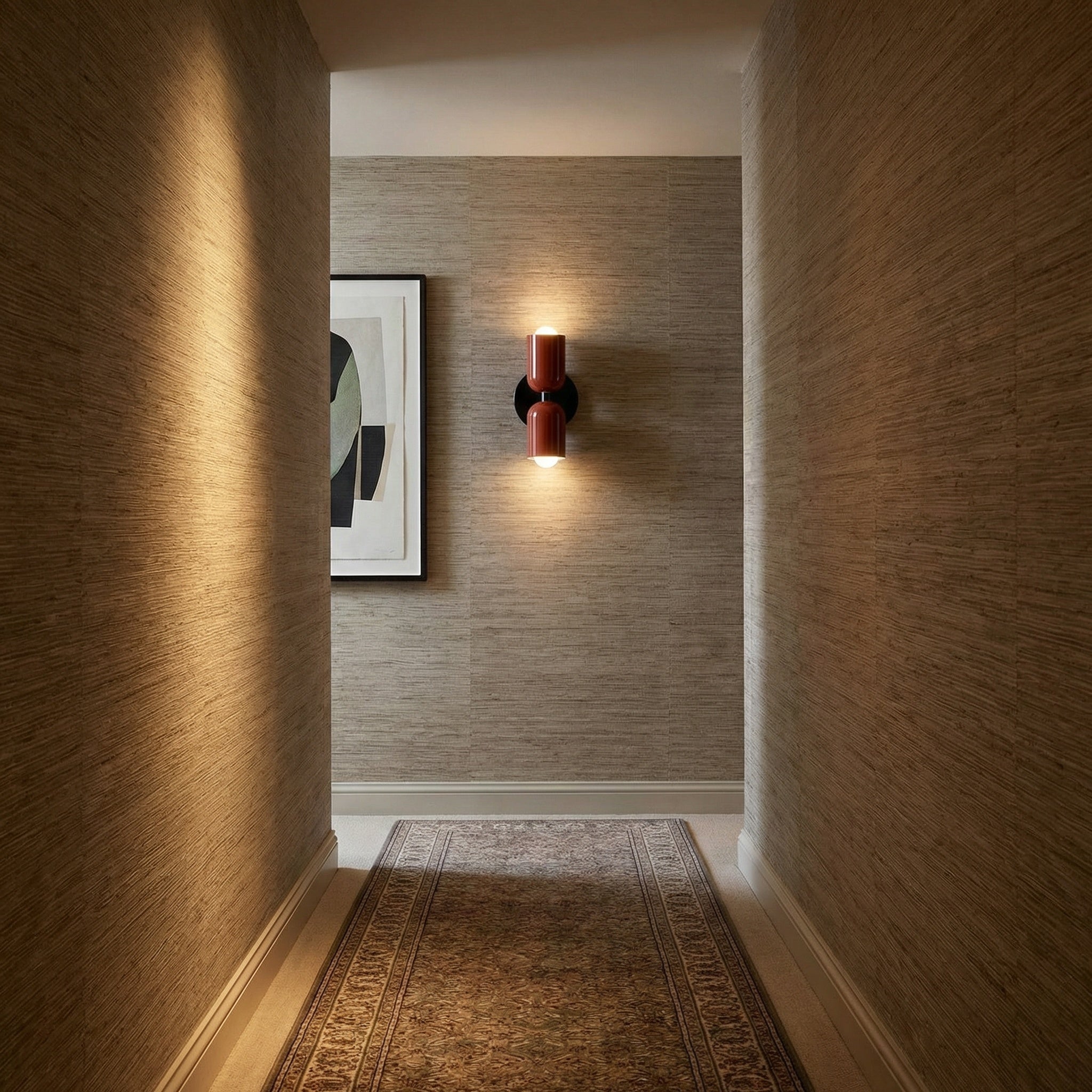 Alvor red wall sconce in a grasscloth hallway, casting light up and down above a runner rug