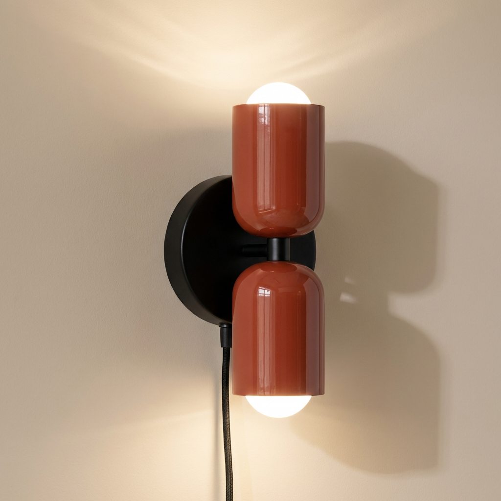 Alvor up-and-down wall sconce lit, red painted metal shades glowing on black round backplate