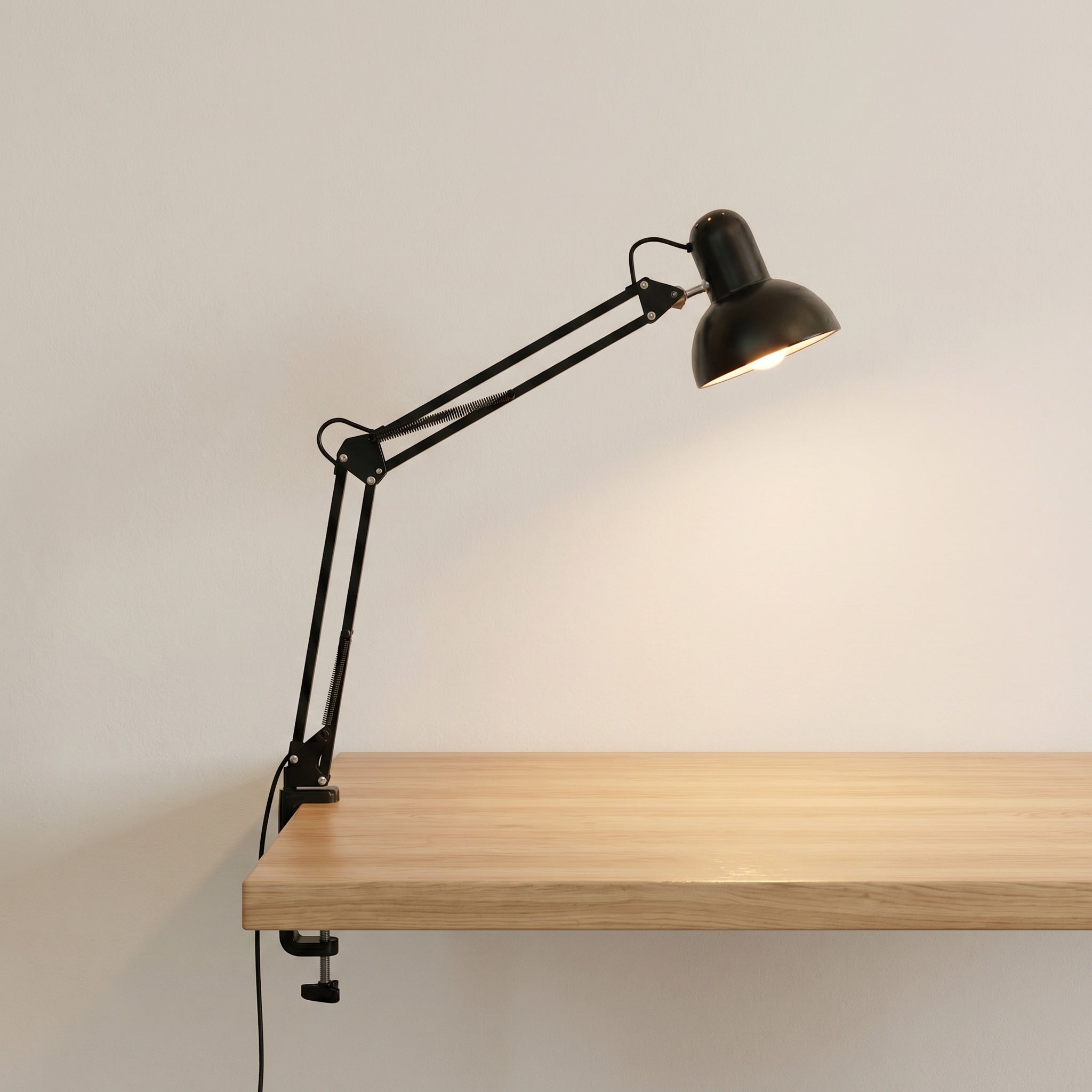 Minimalist clip-mount table lamp with retractable arm in black, product shot on a desk.