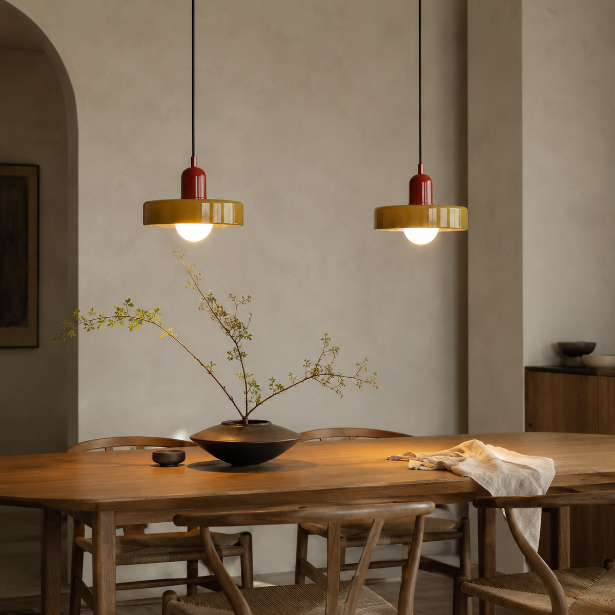 Bragança disc and globe pendant light in red, hung as a row of 2 in a dining room.