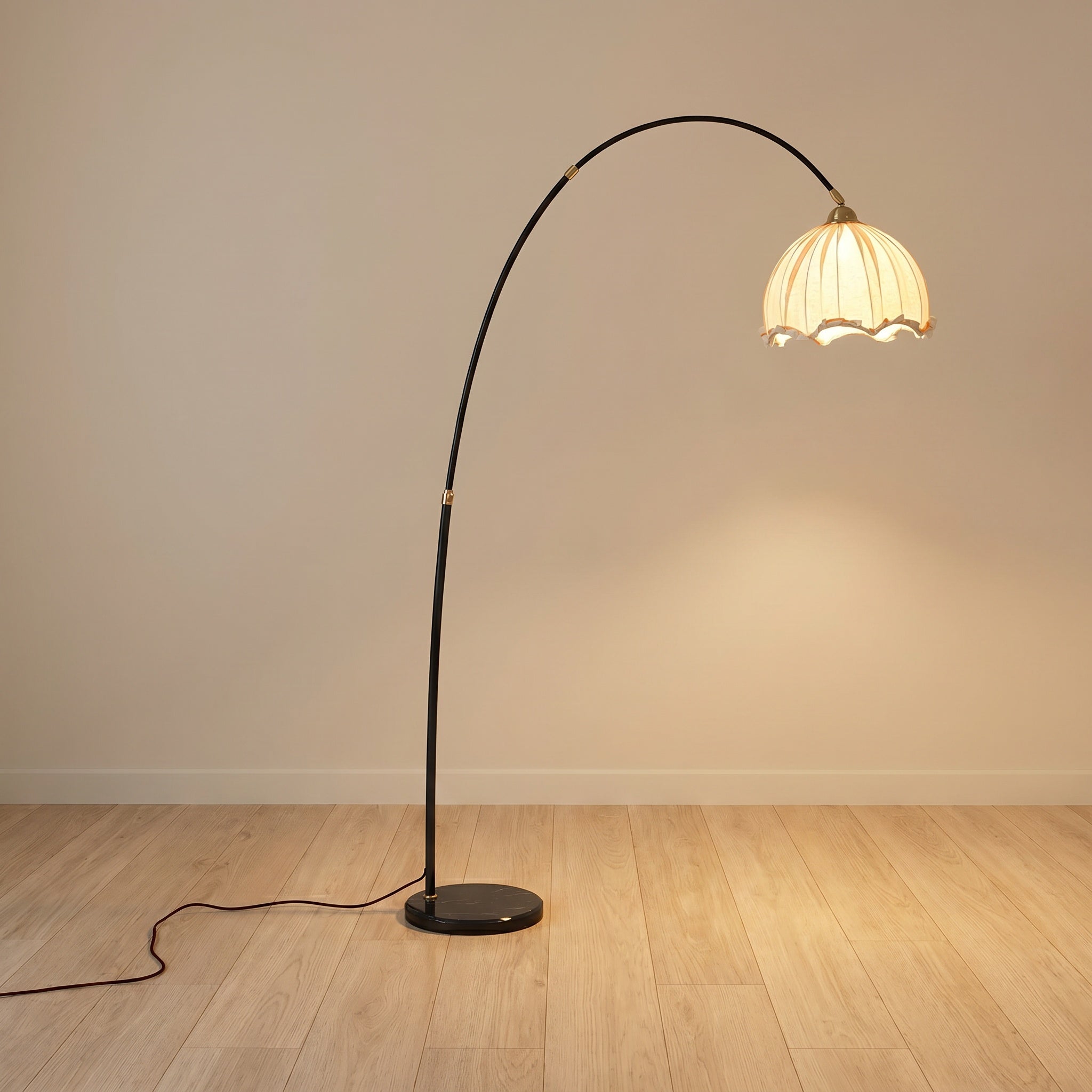 Arc floor lamp with black stem and white scalloped fabric shade on a black marble base, product shot.