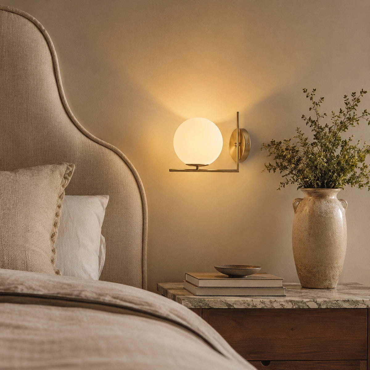 Ceira globe wall sconce with a brass right-angle bracket and an opal white globe, shown in a room