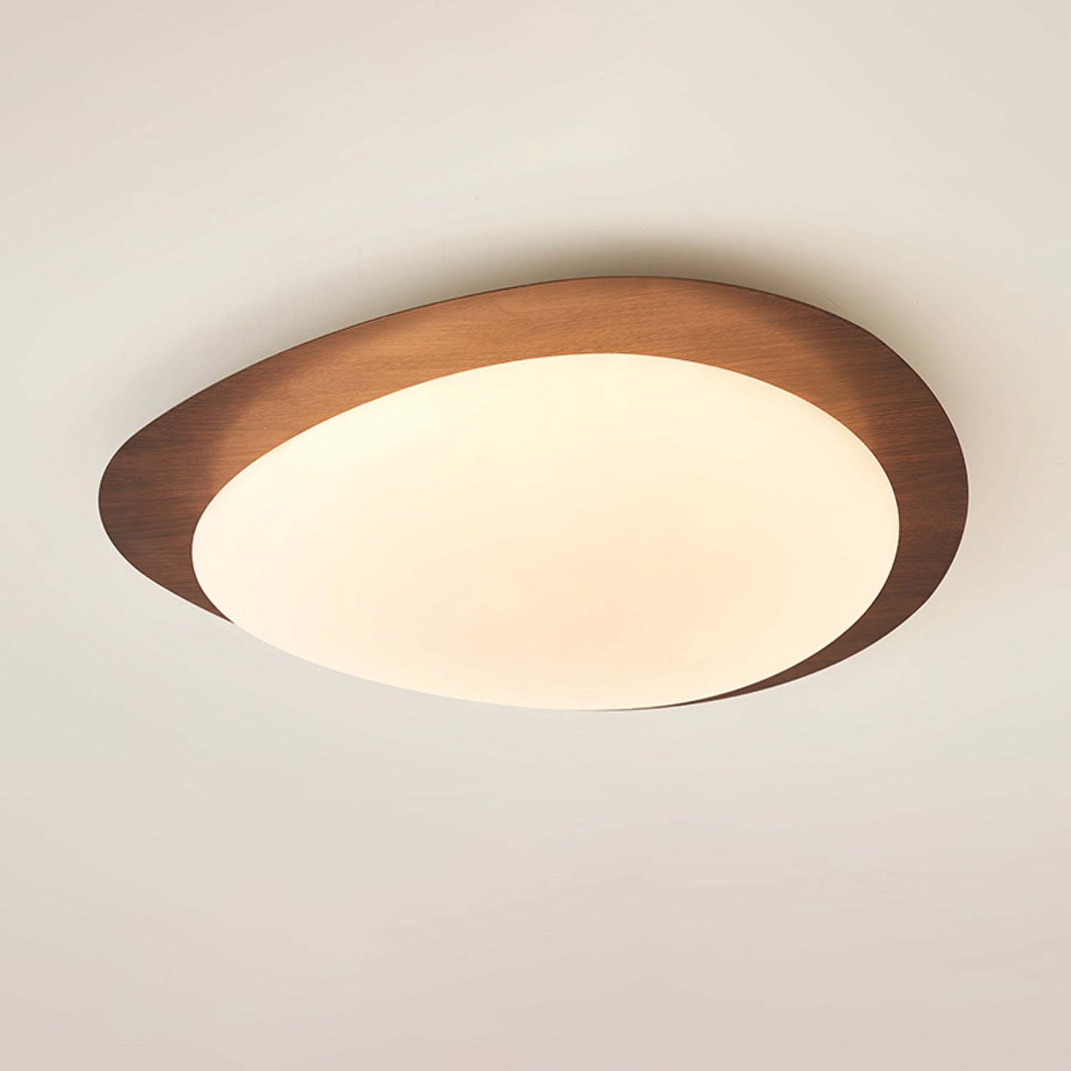 Ericeira pebble form flush mount ceiling light in walnut grain, ceiling-mounted detail shot