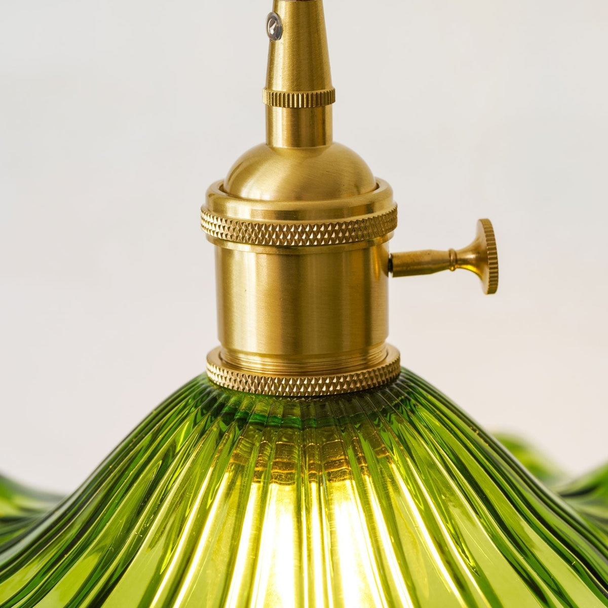 Brass socket with knurled rings and turn-key switch above ribbed green glass.