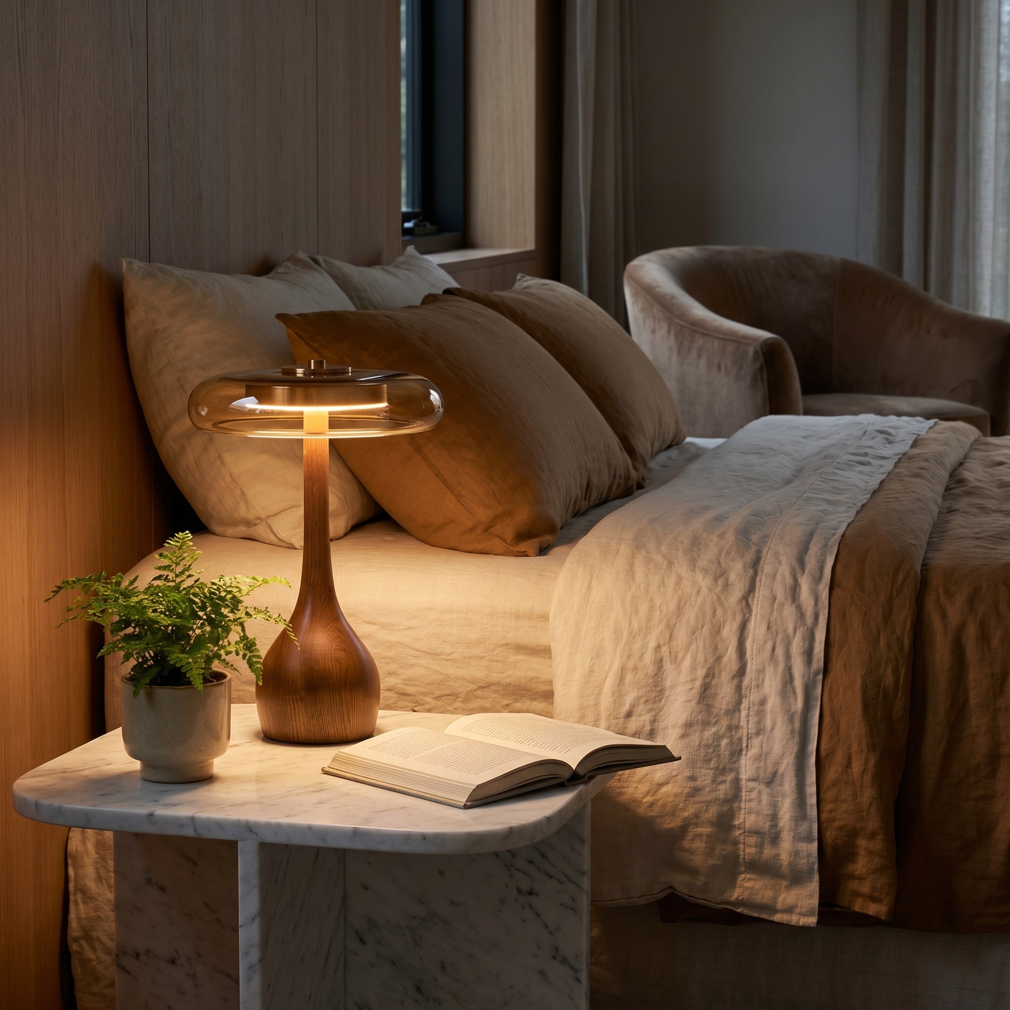 Walnut wooden table lamp with amber dome on a marble bedside in a beige bedroom.