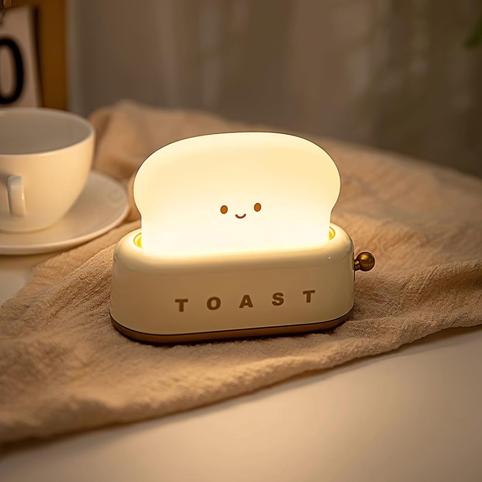 Portable toaster-shape LED night light in almond yellow with smiling toast face, product shot.
