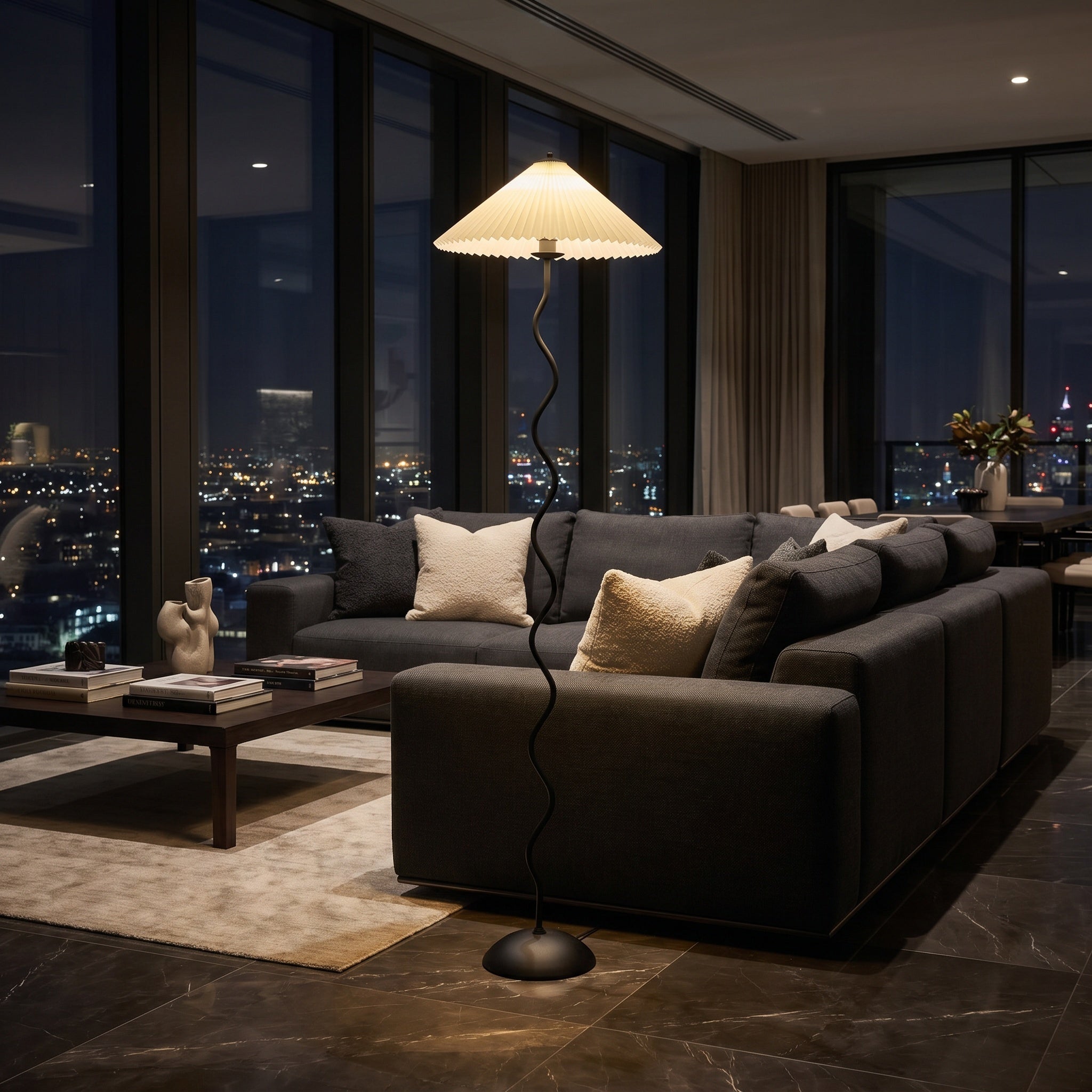 Wavy-stem floor lamp with beige shade above a dark sectional in a city penthouse.