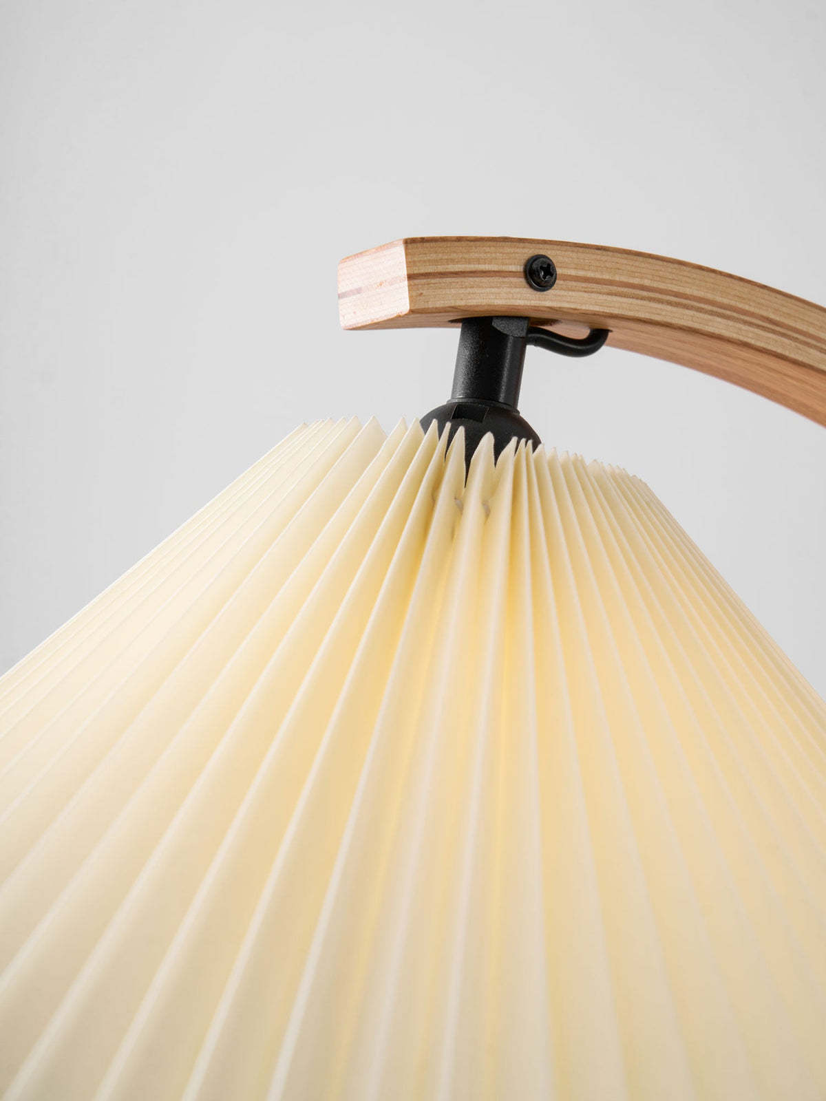 Pleated shade apex and screwed beech arm joint with black mount on the Tomar floor lamp.
