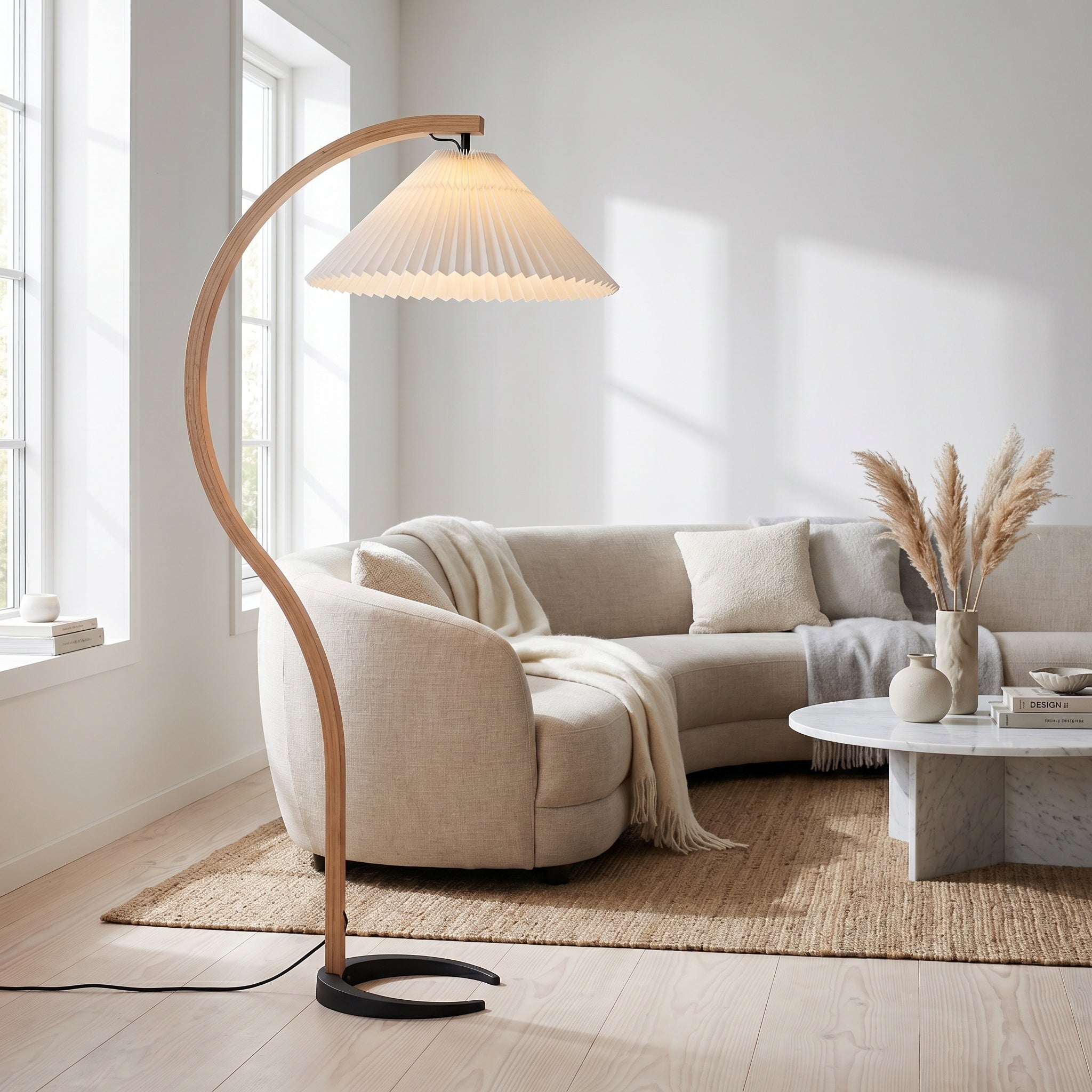 Bentwood beech floor lamp with white pleated shade beside a curved Scandinavian sofa.