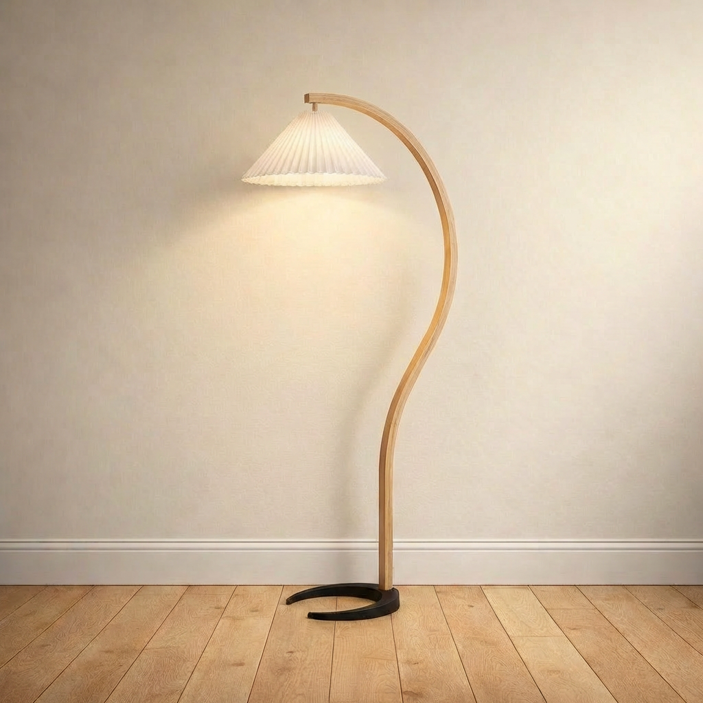 Bentwood beech floor lamp with a pleated white linen shade on a plain wall over wood floors.