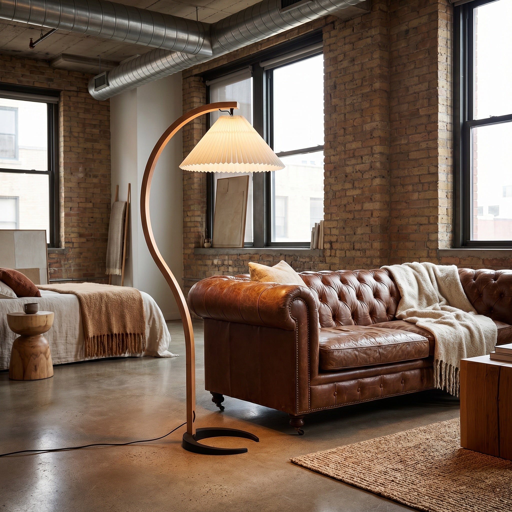 Bentwood beech floor lamp with white pleated shade in a brick loft with leather chesterfield.