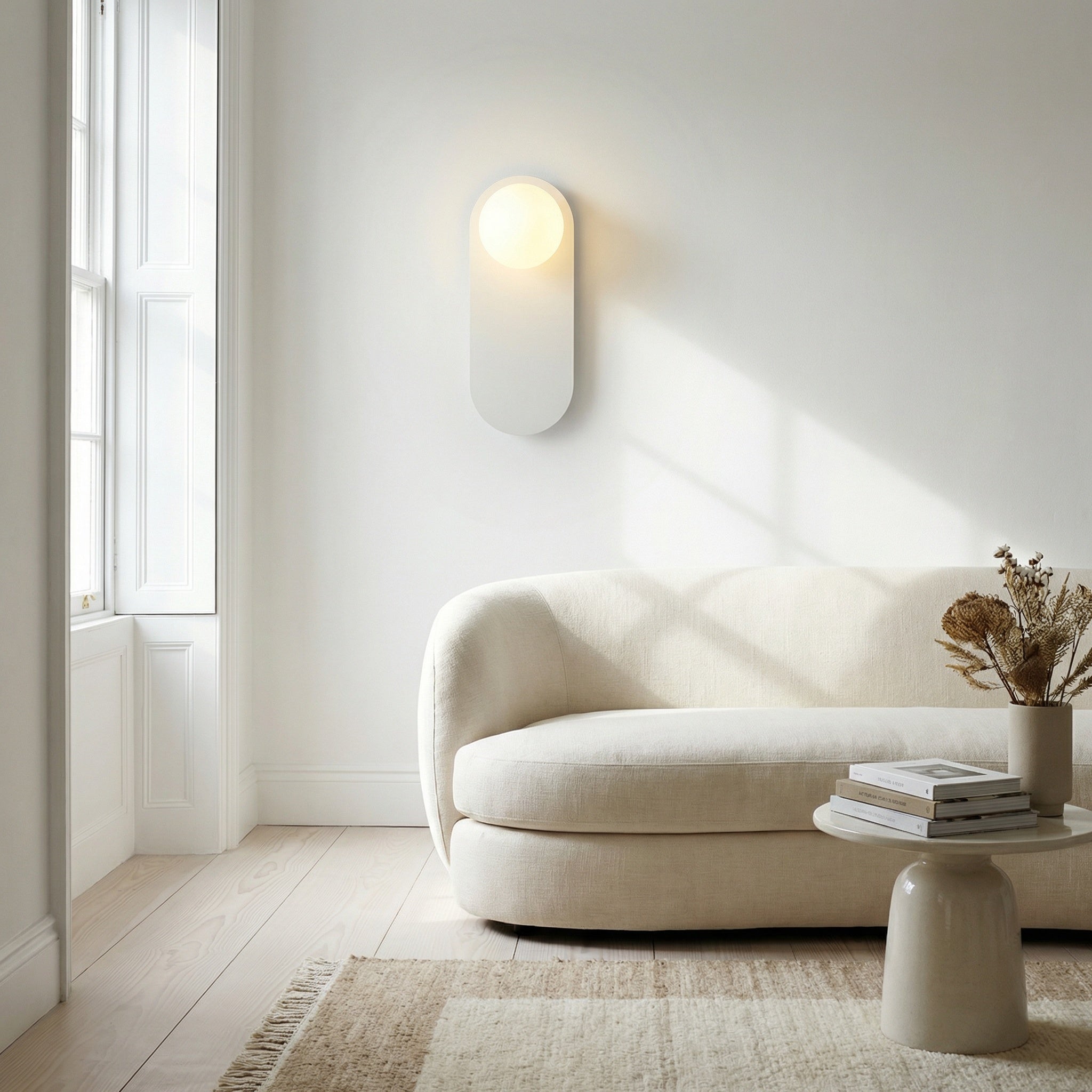Valença wall sconce on a living room wall next to framed art and shelving